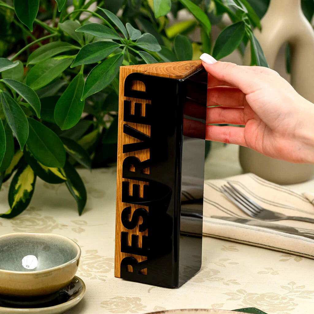 Sophisticated restaurant table reservation sign featuring a premium combination of warm natural wood and sleek black acrylic. The cutout lettering creates a high-end, tactile feel, making it an ideal choice for elegant dining environments