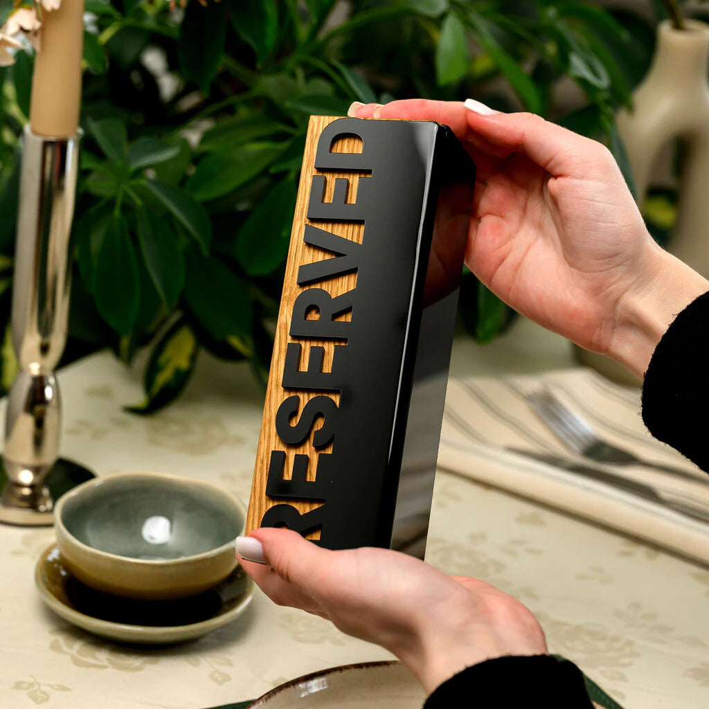 Premium wooden table reservation sign with a minimalist black acrylic design. This high-quality triangular accessory adds a sophisticated touch to any professional restaurant or cafe table setting