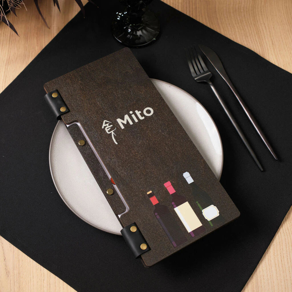 A wenge-colored wooden menu folder features high-quality UV printing, including the white "Mito" logo and three stylized wine bottles in various colors at the bottom. The folder is held together by black leather straps with brass rivets and is presented on a white plate with black cutlery.