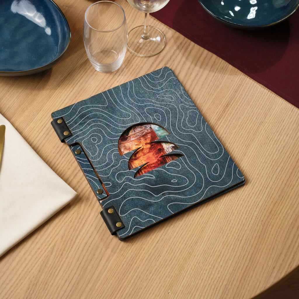 Handheld view of a modern "Reserved" table sign with a black acrylic plate and natural oak wood base, styled in a cozy cafe setting