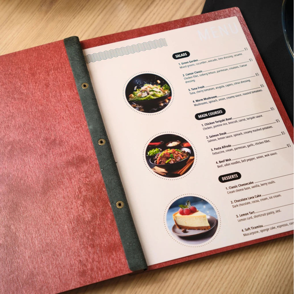 Internal view of an open red wooden menu folder showcasing printed menu inserts with categories for salads, main courses, and desserts. The handcrafted wood menu cover features a secure black leather hinge and bronze bolt binding