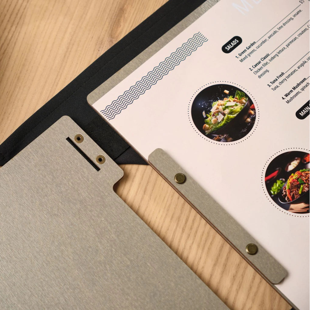 Close-up of an open grey wooden menu folder showcasing the internal bolt binding system. The handcrafted wood menu cover features a precision-cut recessed spine with bronze metal hardware and professional printed menu inserts, highlighting durable restaurant presentation