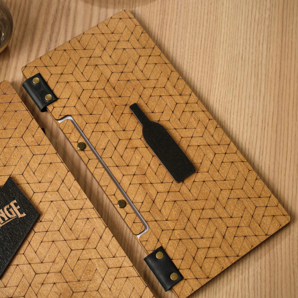 An oak-colored wooden menu folder featuring a full-surface laser-engraved geometric pattern of interlocking hexagons and triangles. The center of the cover is adorned with a prominent black decorative inlay in the shape of a wine bottle. The folder is constructed with black leather hinges secured by gold-toned rivets and features a visible spine with brass binding screws.