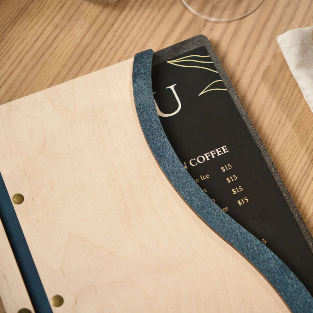 Top-down close-up of a custom wavy wood menu board in Ivory, featuring a blue Jeans-textured accent that frames a black menu insert