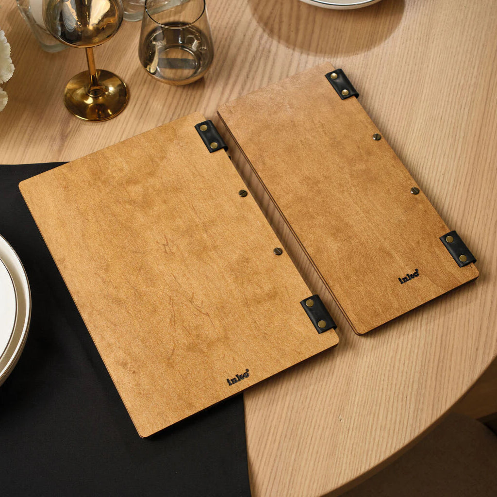 The back side of wooden menu and wine list covers made of smooth oak, featuring a small embossed "inko" logo and leather elements