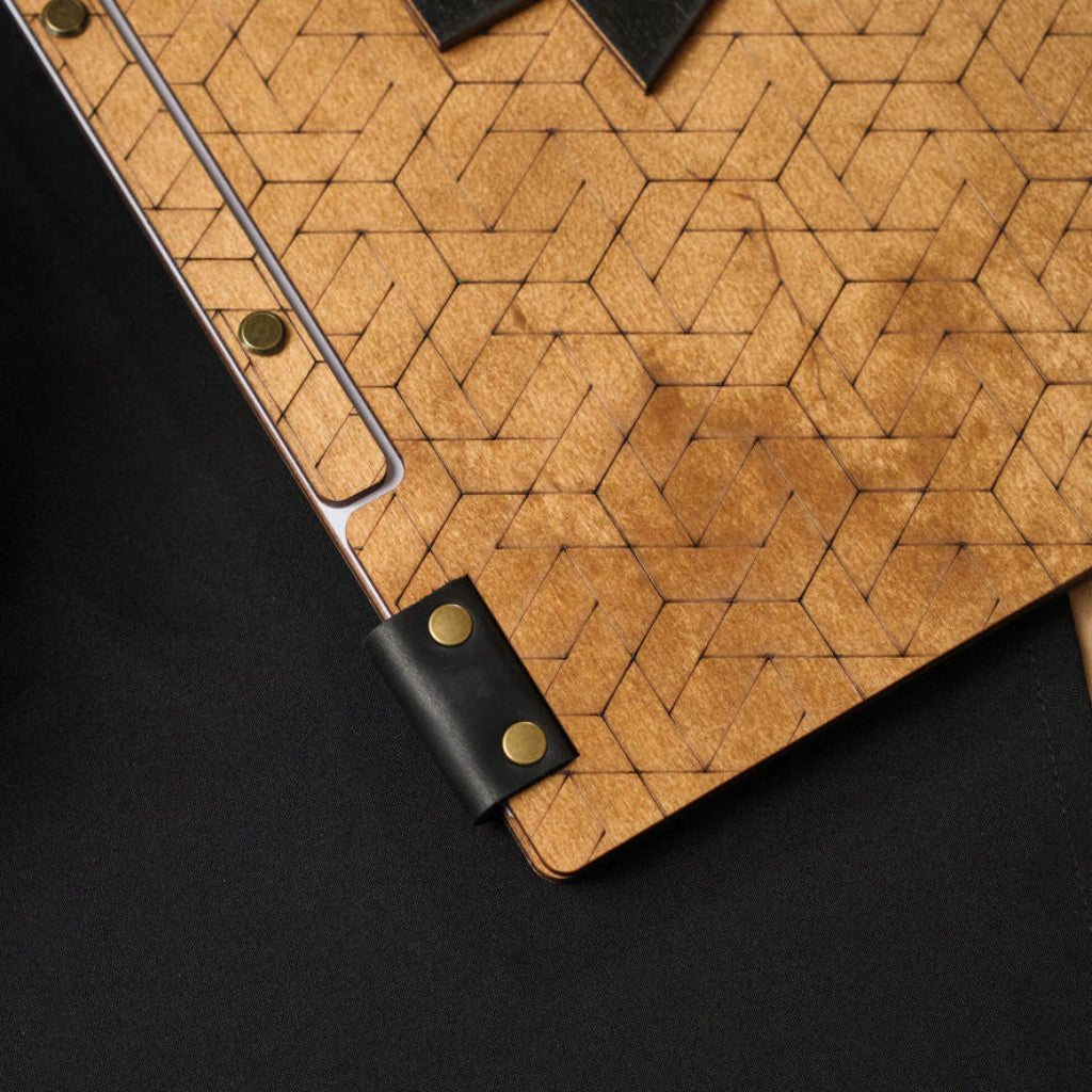 Close-up of a wooden folder with geometric engraving, showcasing the quality of the black leather binding and brass rivets