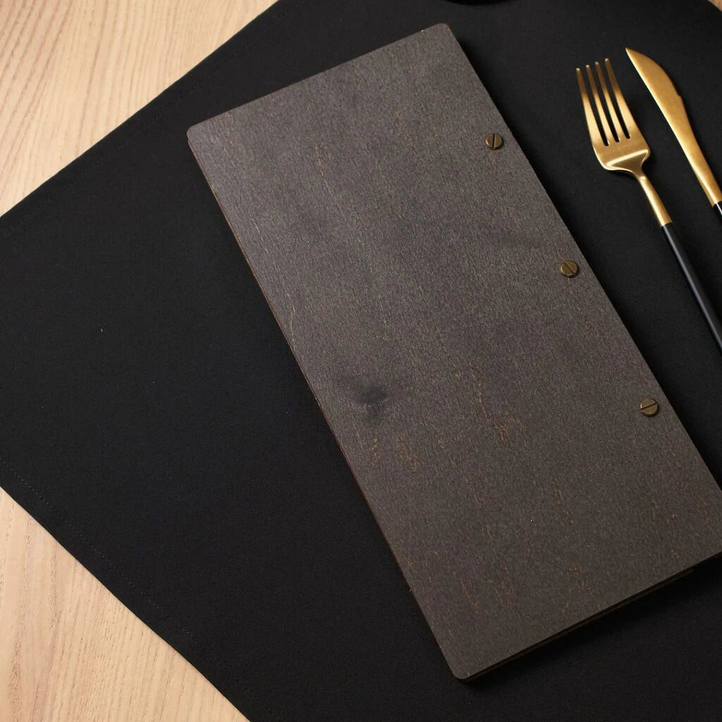 The back view of the walnut menu folder, showing the smooth dark wood grain and three brass-colored screws used for the binding.