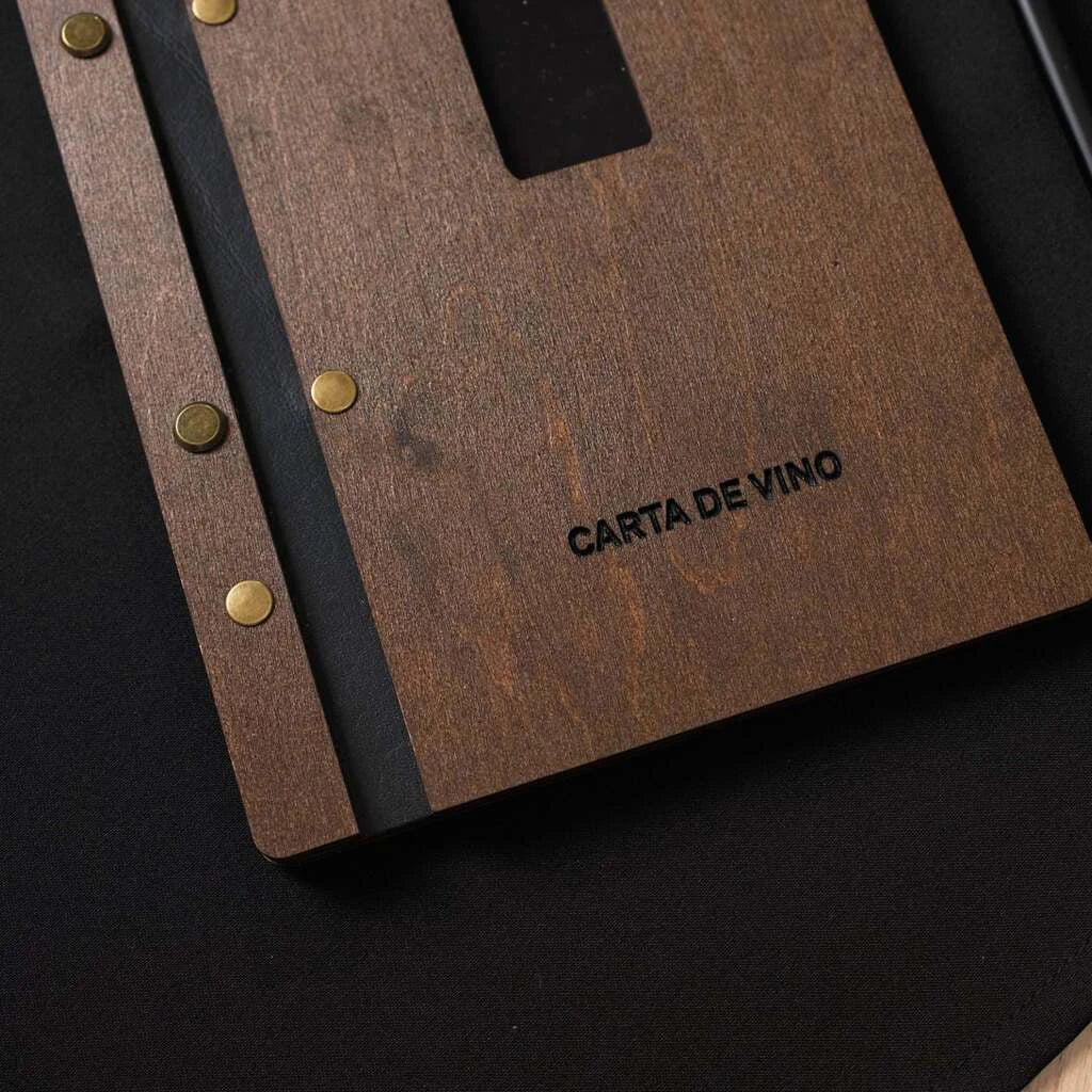 A detailed shot of the lower front cover, highlighting the engraved text "CARTA DE VINO" in black ink and the brass rivets along the binding edge.