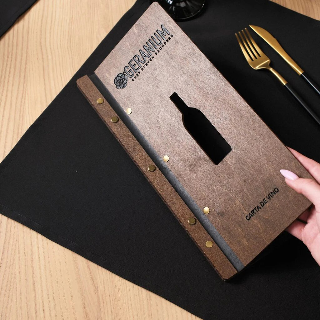 An angled close-up of the walnut menu on a table, highlighting the tactile texture of the wood and the clean edges of the wine bottle cutout.
