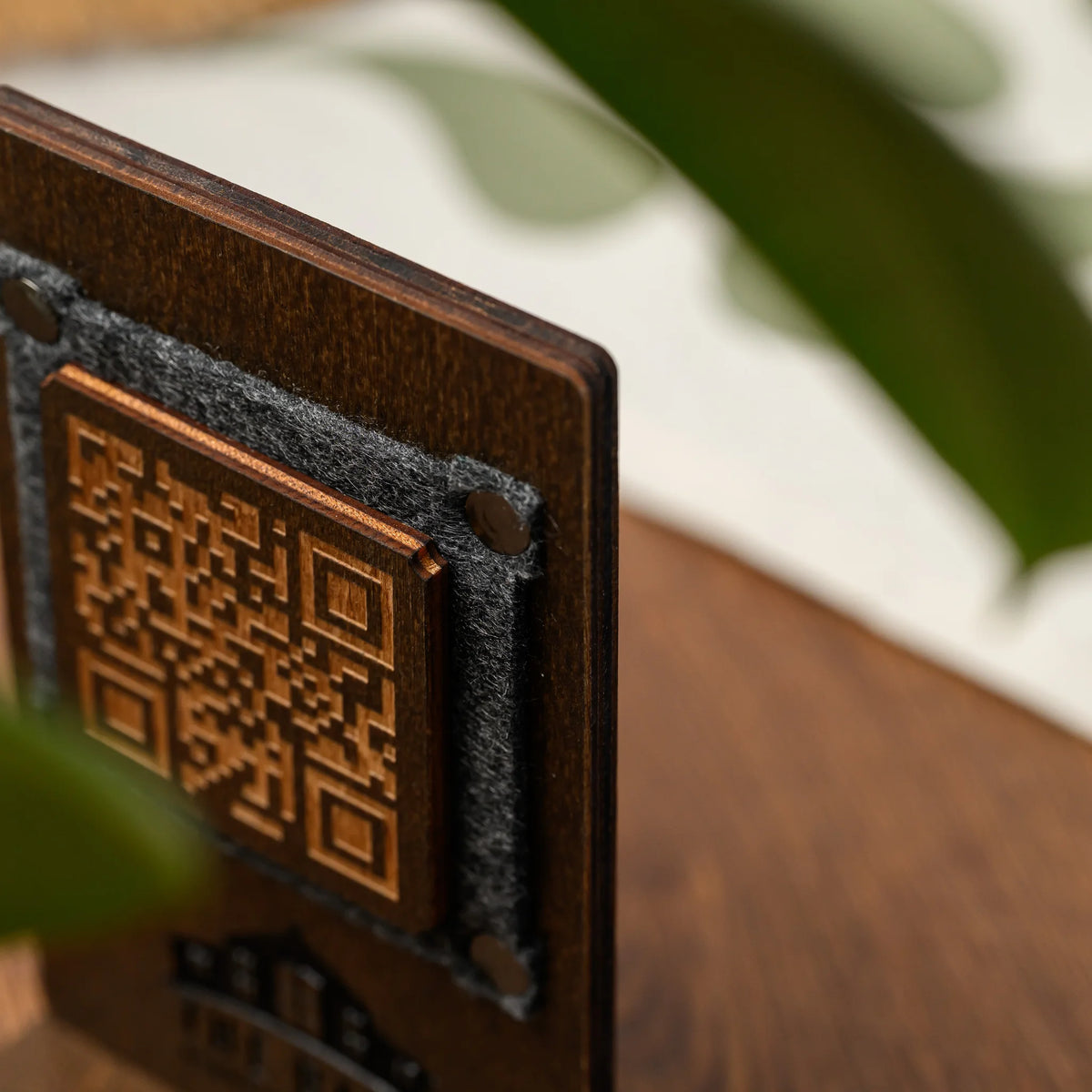 Фанерний QR стенд з гравіюванням, кут зблизька: фанерна пластина з QR-кодом на сірому фетрі, хольнітени та шари фанери 4 мм на торці
