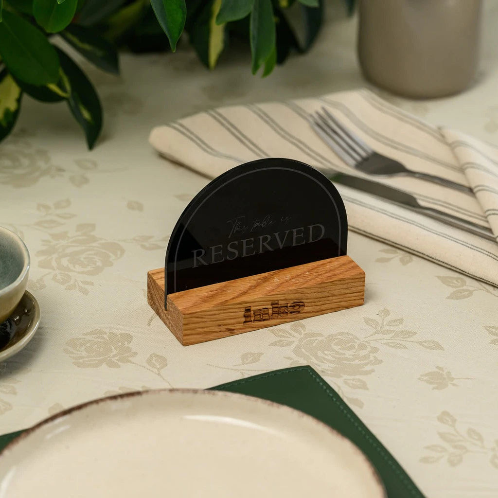 Semicircle black acrylic 'Reserved' table sign on a wooden base with engraved logo