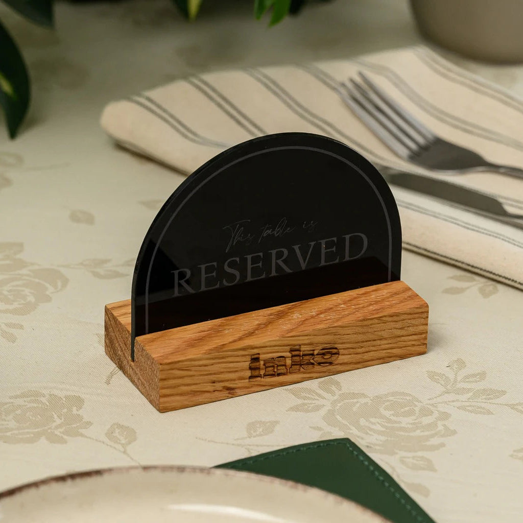 Vertical wooden 'Reserved' sign with black acrylic plate on a restaurant table