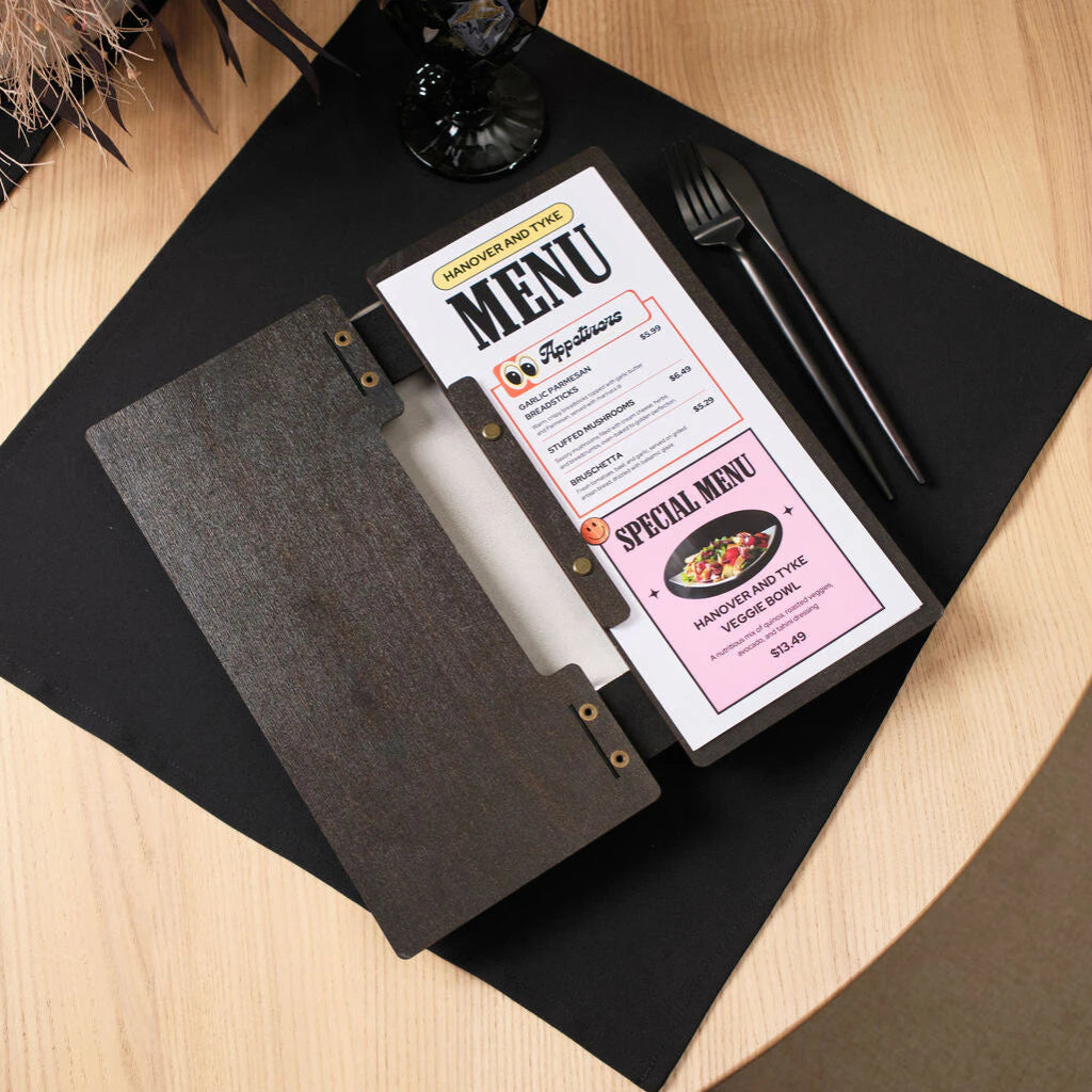The opened wenge menu folder reveals a colorful printed insert titled "Hanover and Tyke MENU," featuring appetizer listings and a "Special Menu" section on a pink background. The interior construction shows the dark wood grain and the brass hardware used for the binding.